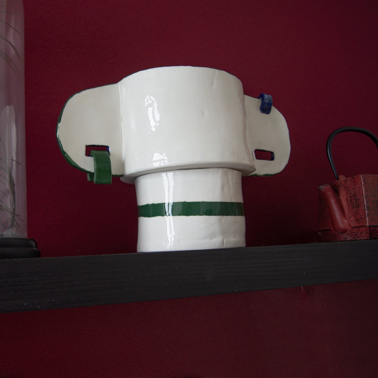 Green ceramic vase featuring ear-shaped handles with metal rings.