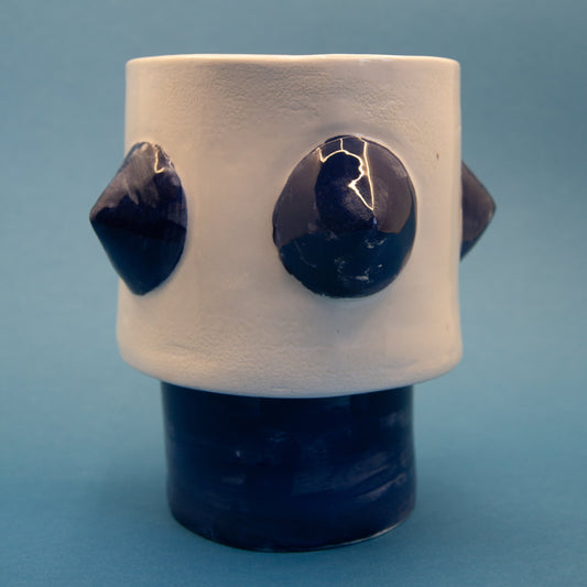 White and blue ceramic planter with bold, sculptural form.